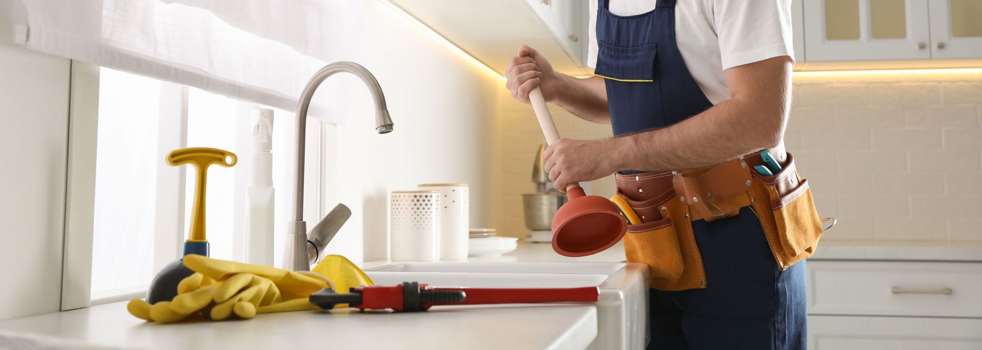 Professional drain cleaning with plumber tools at kitchen sink